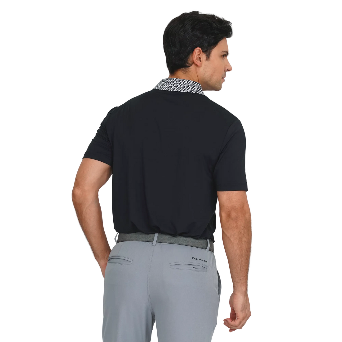 Man wearing a levelwear black polo shirt and gray pants on a light gray background