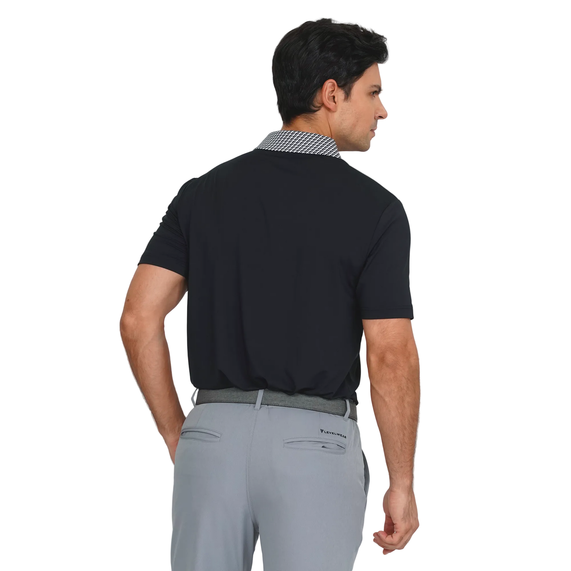 Man wearing a levelwear black polo shirt and gray pants on a light gray background