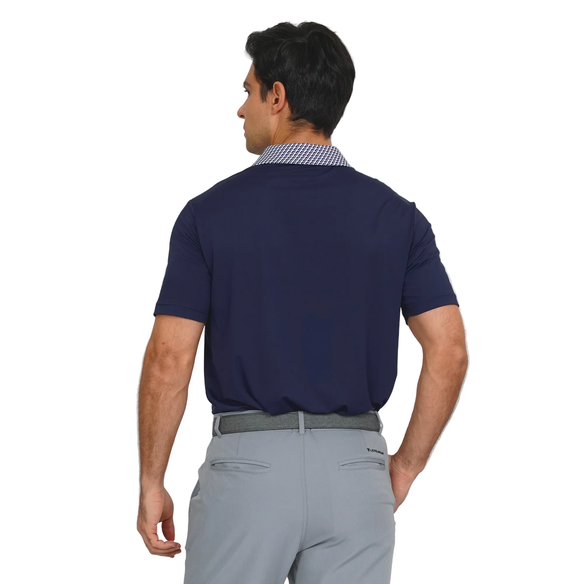 Man wearing a Levelwear navy blue polo shirt and gray pants on a light gray background