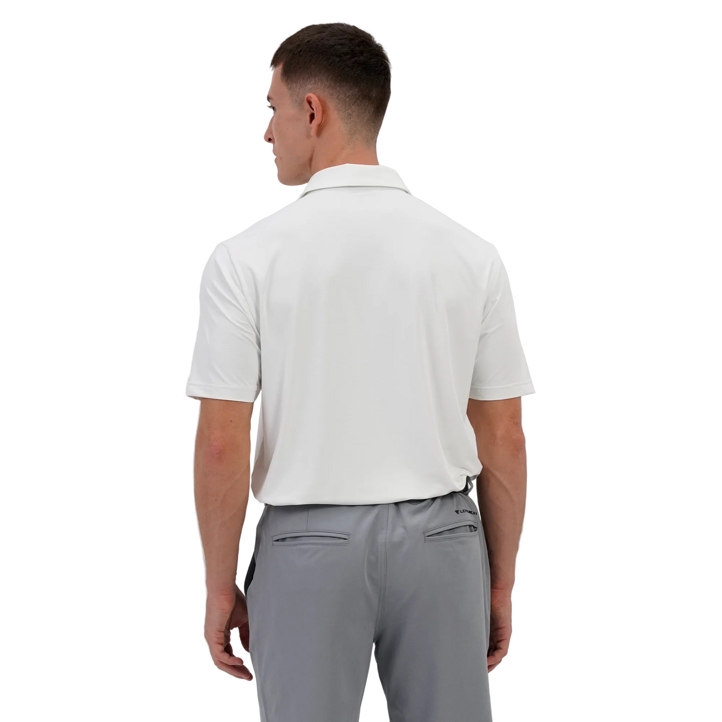 Man wearing a Levelwear white polo shirt and gray pants on a plain background